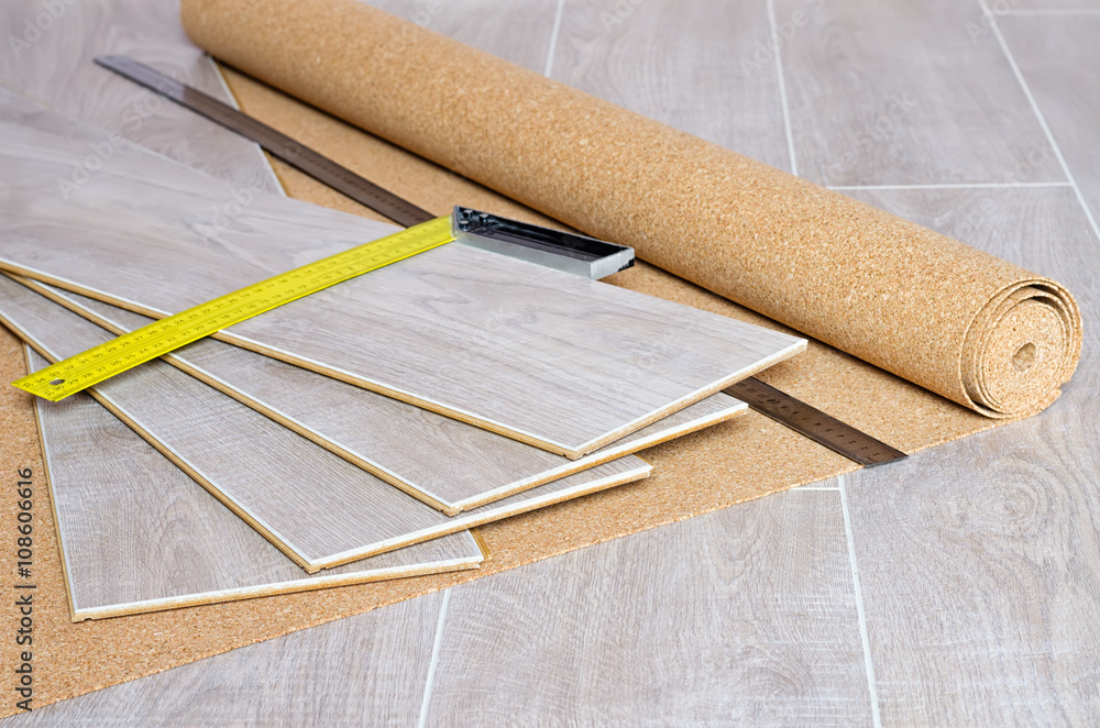Grey laminate flooring plans with a roll of underlay and tape measure
